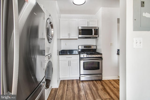 kitchen featuring electric panel, white cabinets, dark wood-style floors, stainless steel appliances, and stacked washing maching and dryer