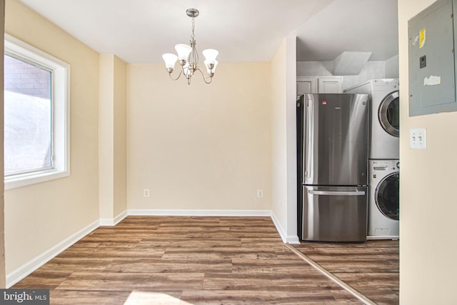 kitchen with stacked washer / dryer, wood finished floors, baseboards, freestanding refrigerator, and electric panel