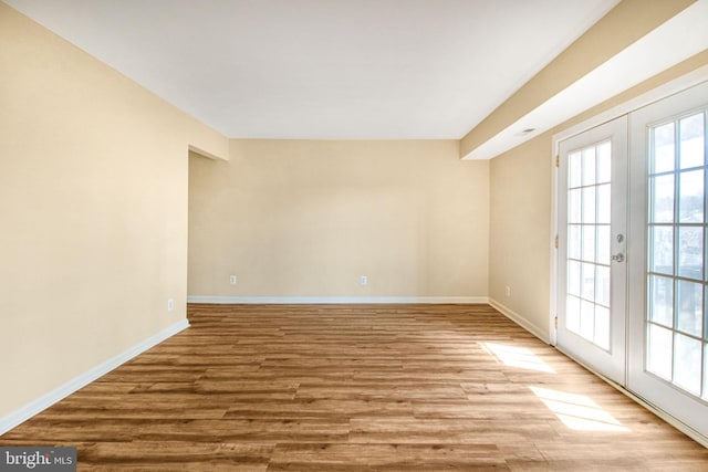 unfurnished room with french doors, baseboards, and wood finished floors