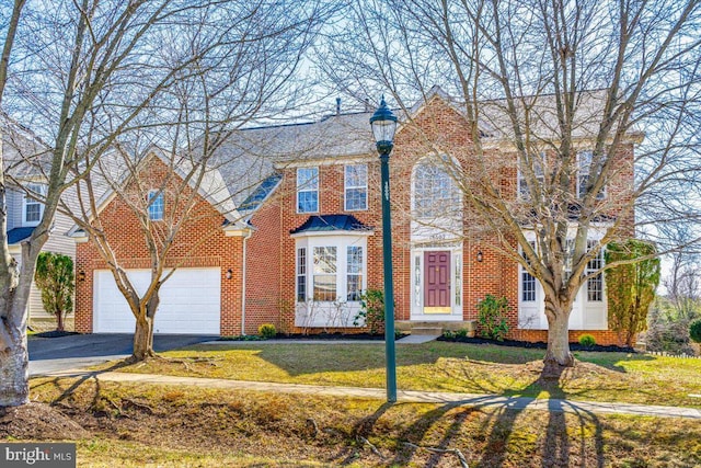 view of front facade featuring brick siding, driveway, an attached garage, and a front lawn