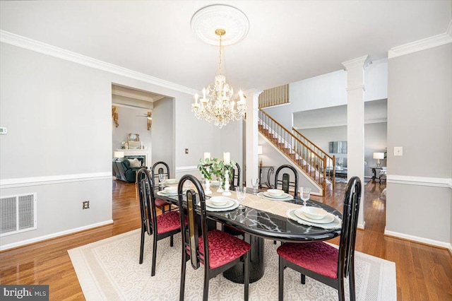 dining space featuring visible vents, crown molding, stairs, and wood finished floors