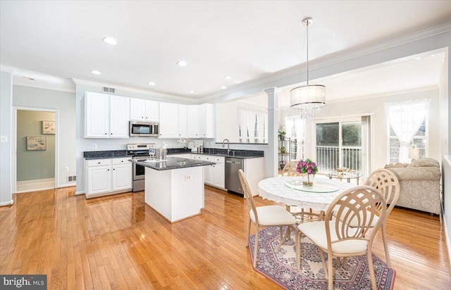 kitchen featuring light wood-type flooring, appliances with stainless steel finishes, white cabinets, and a center island