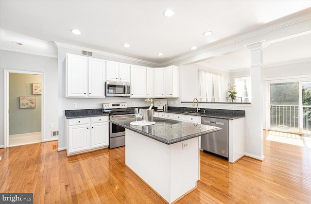 kitchen featuring visible vents, a sink, stainless steel appliances, white cabinets, and light wood-type flooring