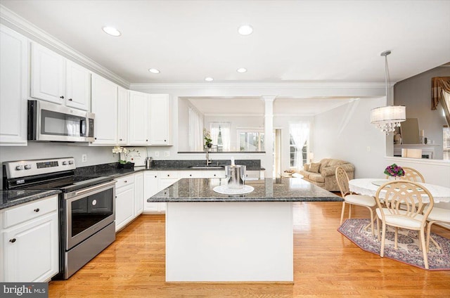 kitchen with light wood finished floors, white cabinets, appliances with stainless steel finishes, and a center island