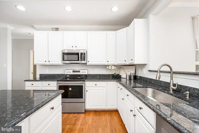 kitchen with a sink, light wood-style floors, appliances with stainless steel finishes, white cabinets, and crown molding