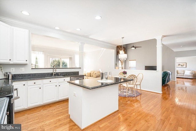 kitchen featuring white cabinetry, decorative columns, open floor plan, and a sink