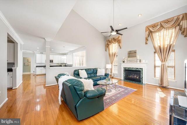 living room featuring light wood finished floors, a ceiling fan, baseboards, and a premium fireplace