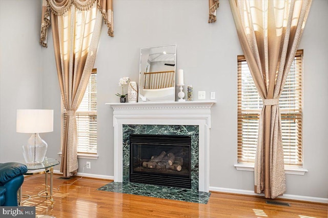 living room with visible vents, baseboards, wood finished floors, and a fireplace