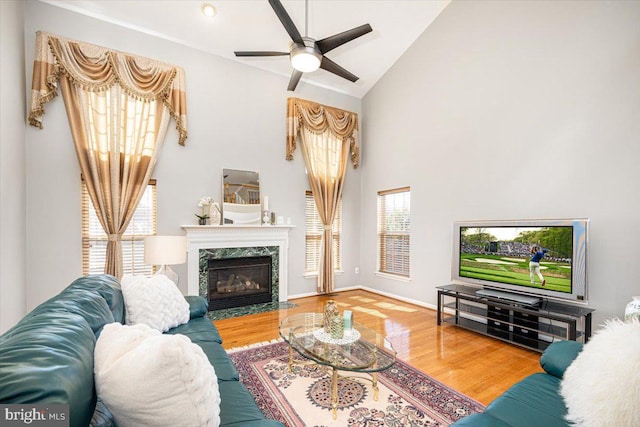 living area featuring high vaulted ceiling, wood finished floors, baseboards, and a premium fireplace