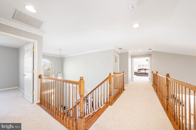 corridor featuring an upstairs landing, visible vents, carpet flooring, and ornamental molding