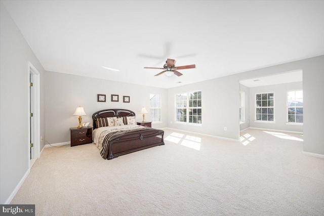 carpeted bedroom featuring multiple windows, a ceiling fan, and baseboards