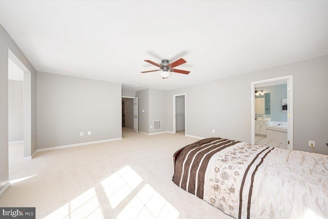 bedroom with visible vents, connected bathroom, a walk in closet, baseboards, and light colored carpet