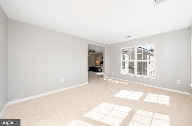 empty room featuring carpet flooring, visible vents, a ceiling fan, and baseboards