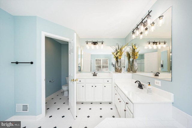 full bath with a sink, visible vents, toilet, and two vanities