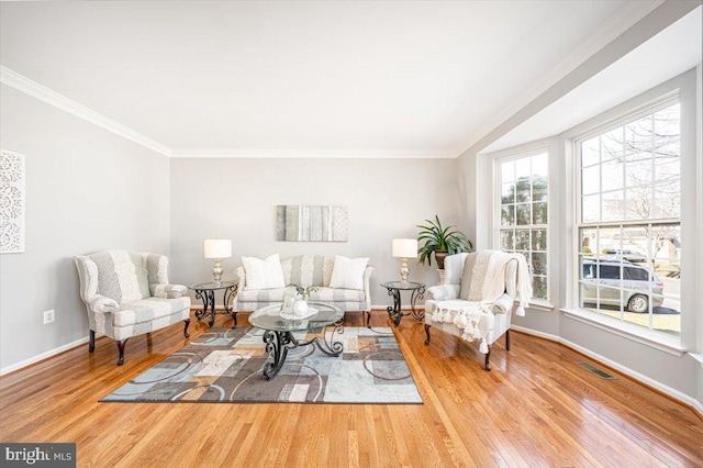 living area with visible vents, ornamental molding, baseboards, and wood finished floors