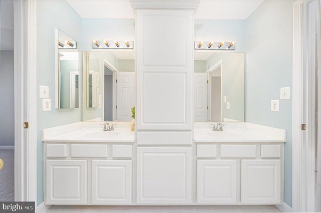 full bath featuring a sink, baseboards, and double vanity