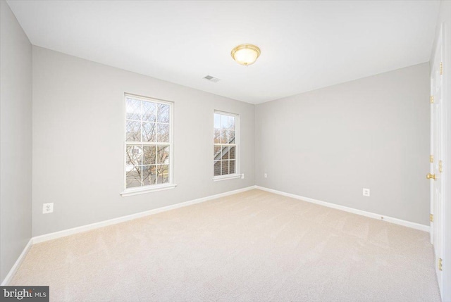 spare room featuring visible vents, baseboards, and light colored carpet