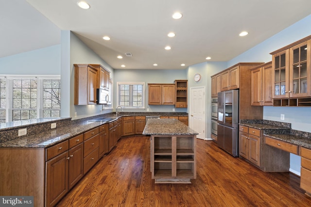 kitchen featuring dark wood finished floors, open shelves, brown cabinets, and appliances with stainless steel finishes