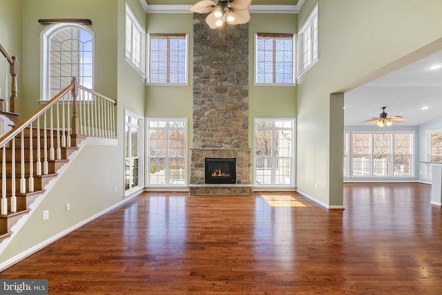 unfurnished living room featuring a wealth of natural light, baseboards, wood finished floors, and a fireplace