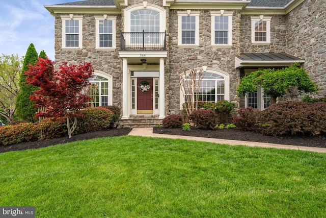 colonial home with a balcony and a front lawn