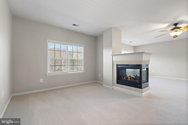 unfurnished living room with baseboards, visible vents, a multi sided fireplace, and carpet floors