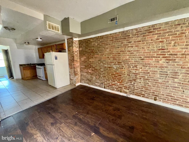 kitchen featuring light wood finished floors, visible vents, brown cabinetry, brick wall, and white appliances