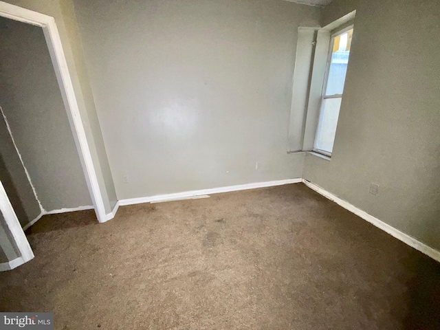 unfurnished bedroom featuring baseboards and dark colored carpet