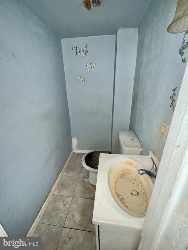 bathroom featuring baseboards, vanity, toilet, and tile patterned floors