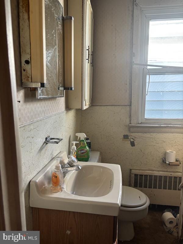 half bath featuring vanity, toilet, and radiator heating unit