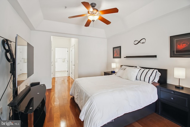 bedroom featuring ensuite bath, ceiling fan, a tray ceiling, and hardwood / wood-style floors