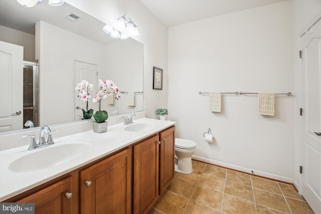 bathroom featuring toilet, double vanity, a sink, and visible vents