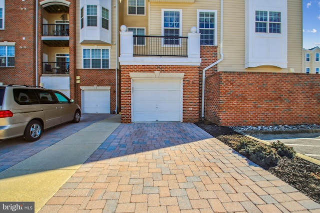 view of front of property featuring driveway, an attached garage, and brick siding