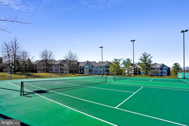 view of tennis court featuring community basketball court, fence, and a residential view