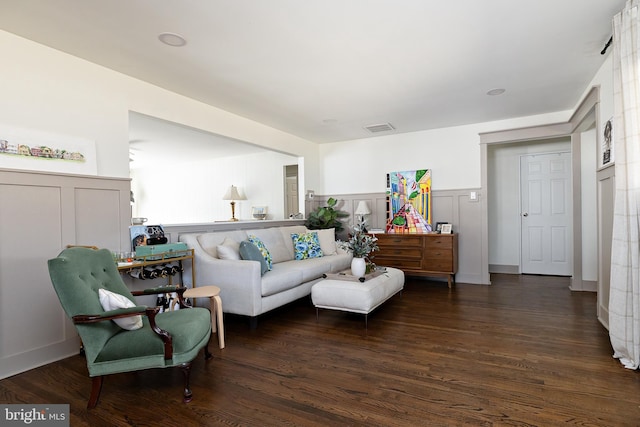 living room with a wainscoted wall, wood finished floors, visible vents, and a decorative wall