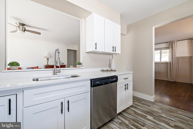 kitchen with light countertops, stainless steel dishwasher, white cabinets, a sink, and wood finished floors