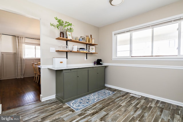 interior space with dark wood-style floors, visible vents, and baseboards