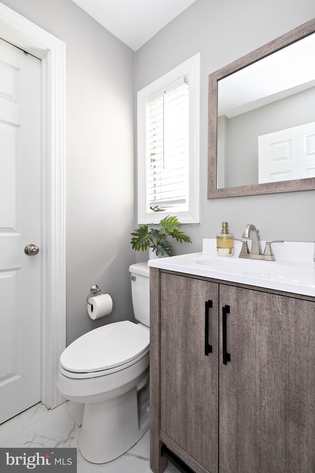 bathroom with marble finish floor, vanity, and toilet