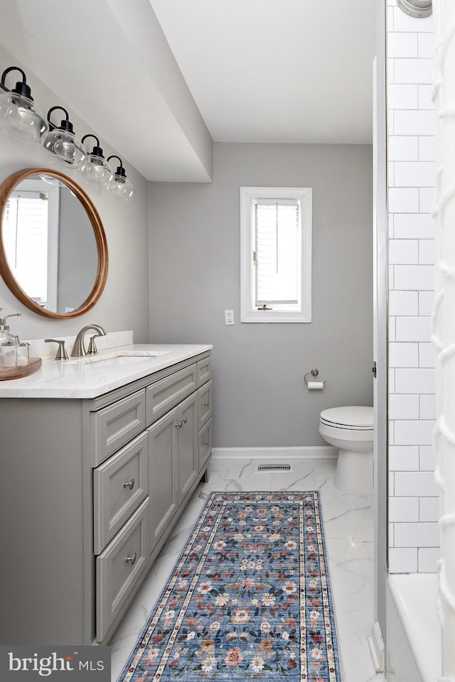 bathroom featuring toilet, vanity, baseboards, marble finish floor, and walk in shower