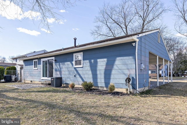 back of property featuring a carport, cooling unit, and a yard