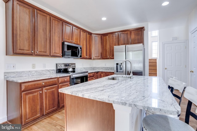 kitchen featuring a breakfast bar, light wood finished floors, stainless steel appliances, and a sink