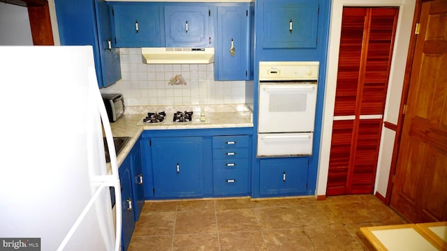 kitchen featuring under cabinet range hood, decorative backsplash, white appliances, blue cabinets, and a warming drawer