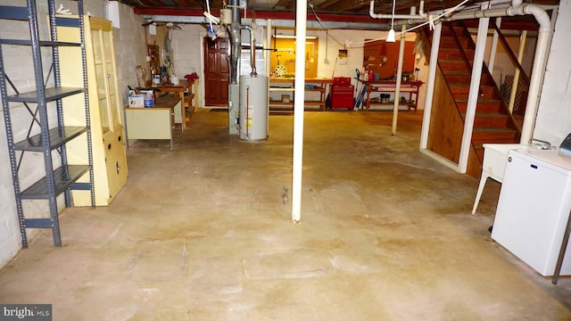 unfinished basement featuring gas water heater, washer / clothes dryer, and concrete block wall