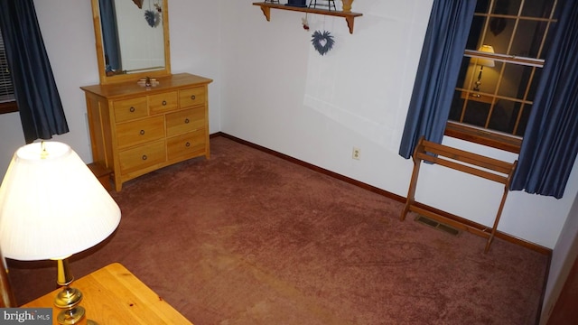 interior space with visible vents, dark carpet, and baseboards