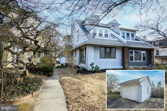 view of front of home featuring a garage, roof with shingles, an outdoor structure, and fence