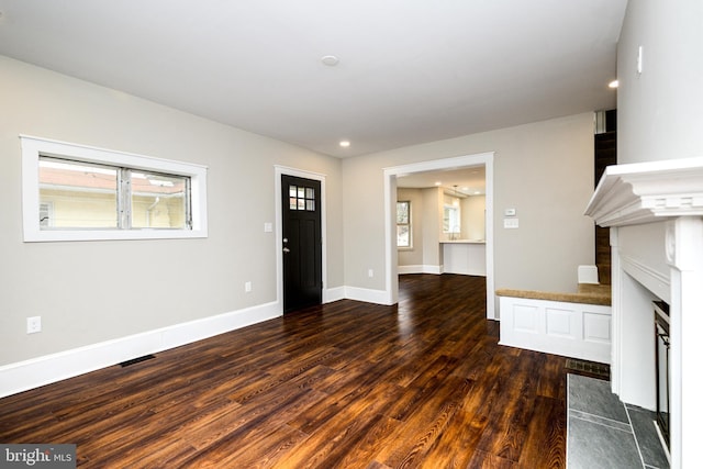 unfurnished living room featuring recessed lighting, visible vents, a fireplace with flush hearth, wood finished floors, and baseboards