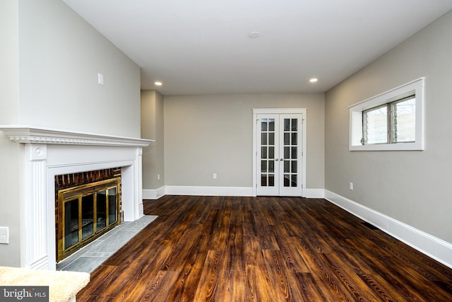 unfurnished living room featuring french doors, recessed lighting, a fireplace with flush hearth, wood finished floors, and baseboards