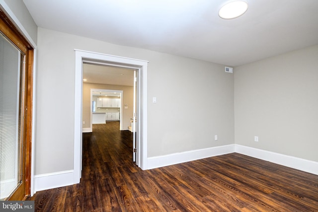 unfurnished room with wood finished floors, visible vents, and baseboards