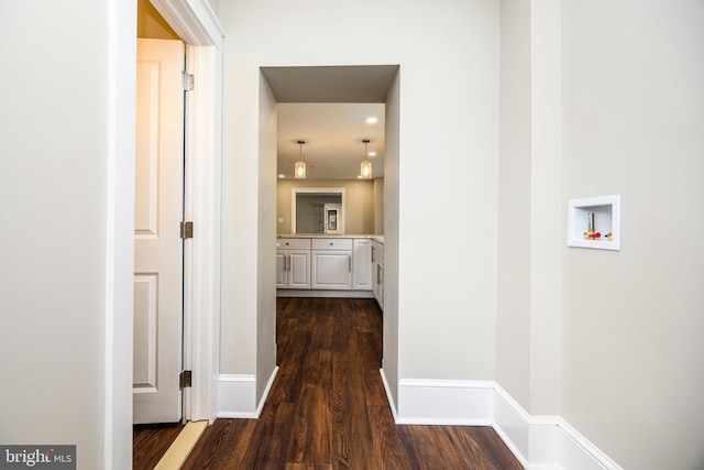 hall featuring dark wood-style flooring and baseboards