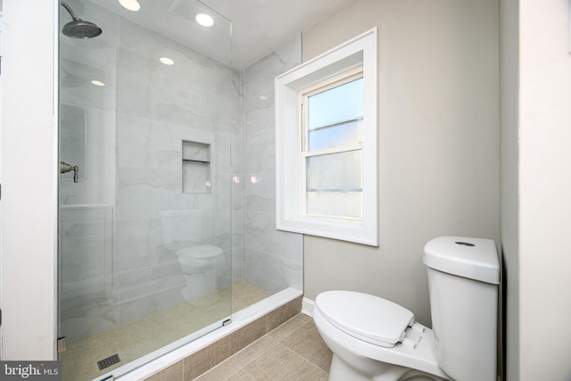 bathroom with tiled shower, toilet, and tile patterned floors