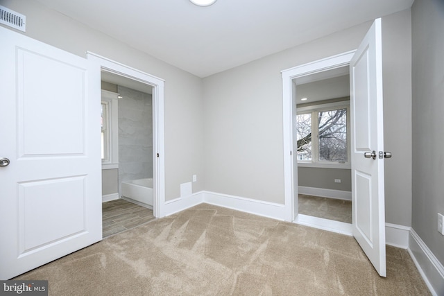 unfurnished bedroom with carpet floors, baseboards, visible vents, and ensuite bathroom